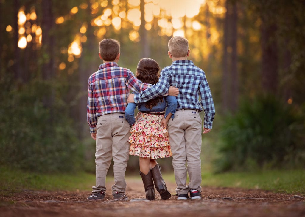 Three young kids with their arms around each other